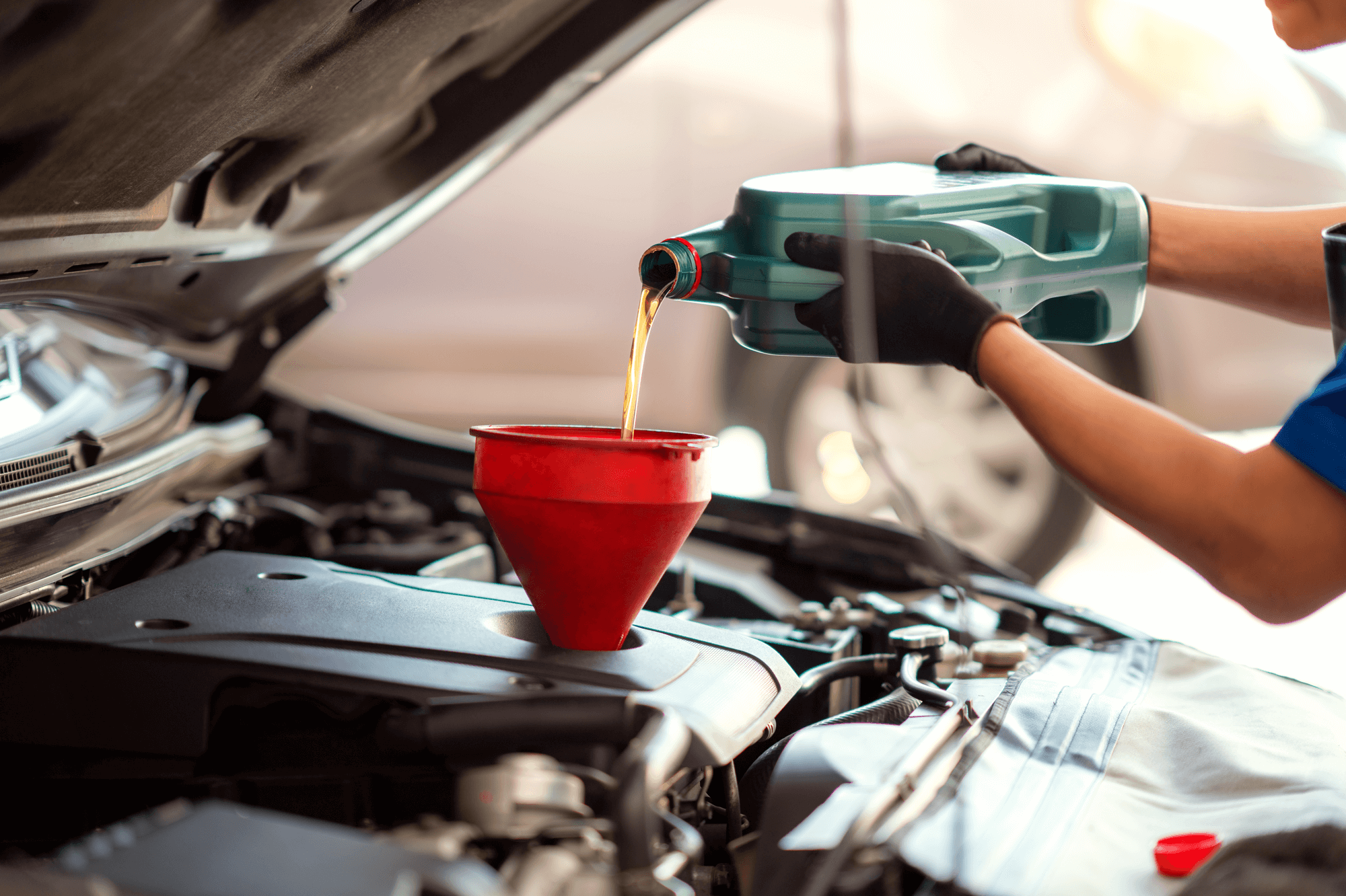 Oil change services for trucks in Palmerston, ON at CDP Diesel and Auto. Image of mechanic pouring fresh oil into the engine on pickup truck in shop.